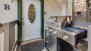 A front door with a green frame and a white door, a metal grill, and a 'B' sign on the wall.