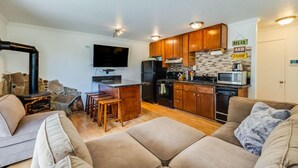 A compact living space with a kitchenette, a flat-screen TV, a stone fireplace, and a sofa. - Tahoe condo across from Heavenly Stagecoach Lodge- (Stateline)