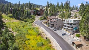 A residential area with a curved road, multiple buildings, and a mountainous backdrop. - Tahoe condo across from Heavenly Stagecoach Lodge- (Stateline)