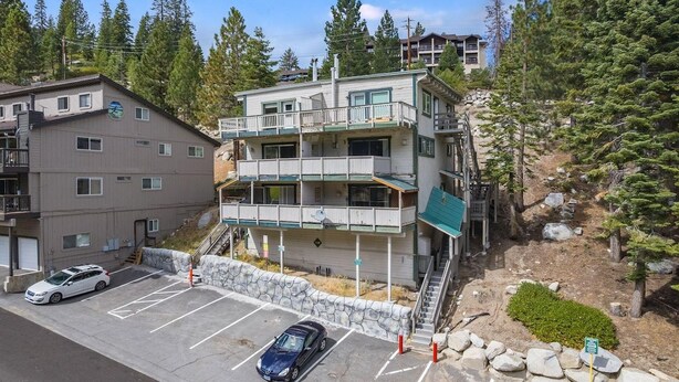 A multi-story building with balconies, a parking lot, and a mountainous backdrop. - Tahoe condo across from Heavenly Stagecoach Lodge- (Stateline)