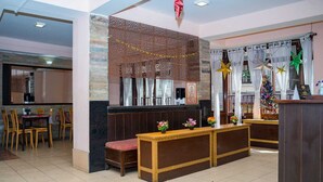 Un vestíbulo de hotel con mostrador de recepción, zona de estar y una pared decorativa.