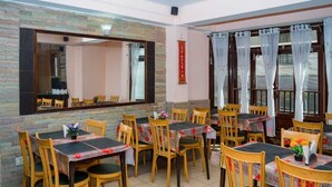 Un restaurante con varias mesas y sillas, paredes de piedra y un espejo grande.