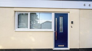 Ein eingeschossiges Gebäude mit einer blauen Tür und einem Fenster mit Rollläden.