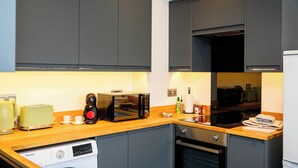 Eine moderne Küche mit grauen Schränken, einer Mikrowelle, einem Toaster und einem Geschirrspüler.