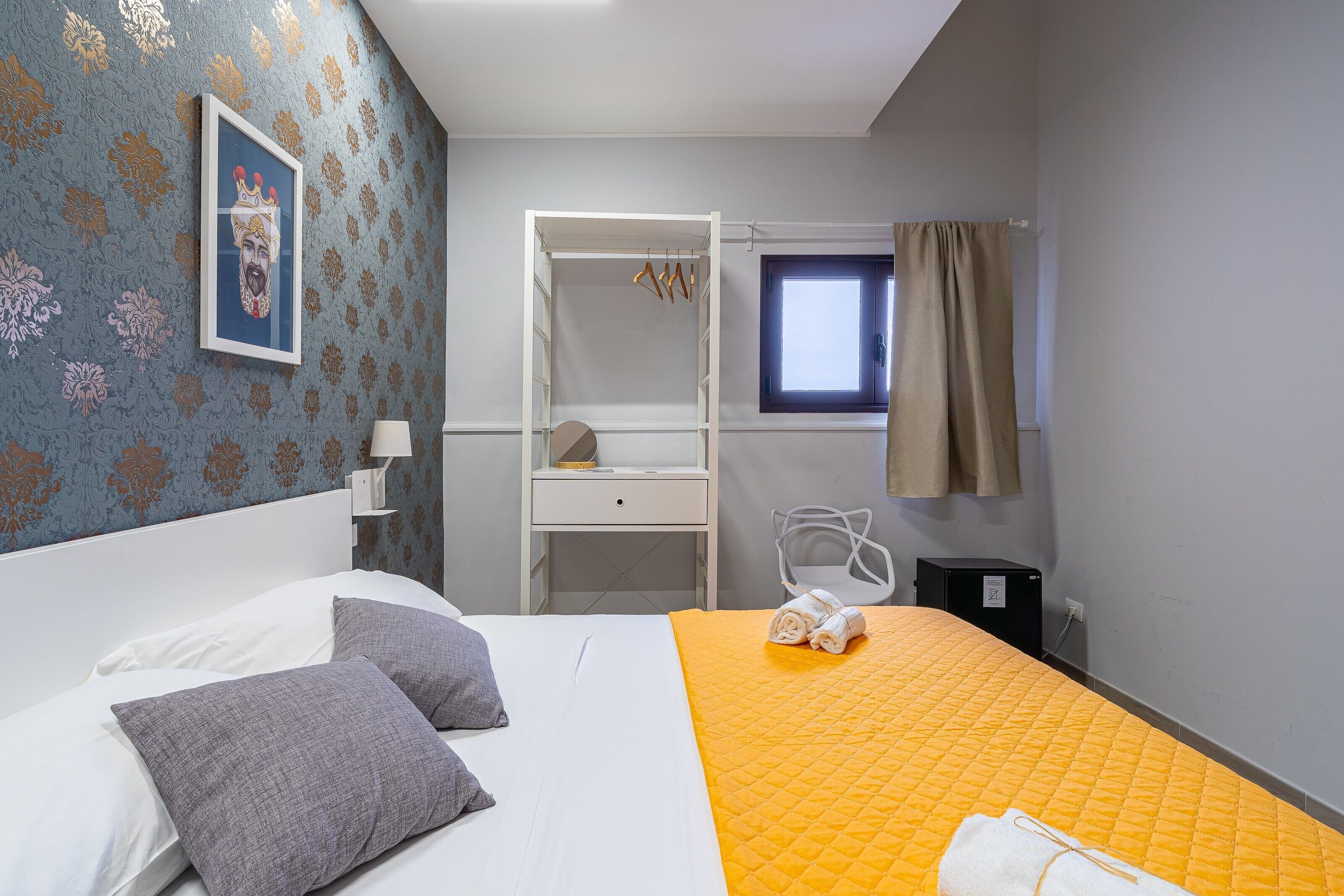 Ett hotellrum med en säng, en garderob, ett skrivbord, en stol och ett fönster.