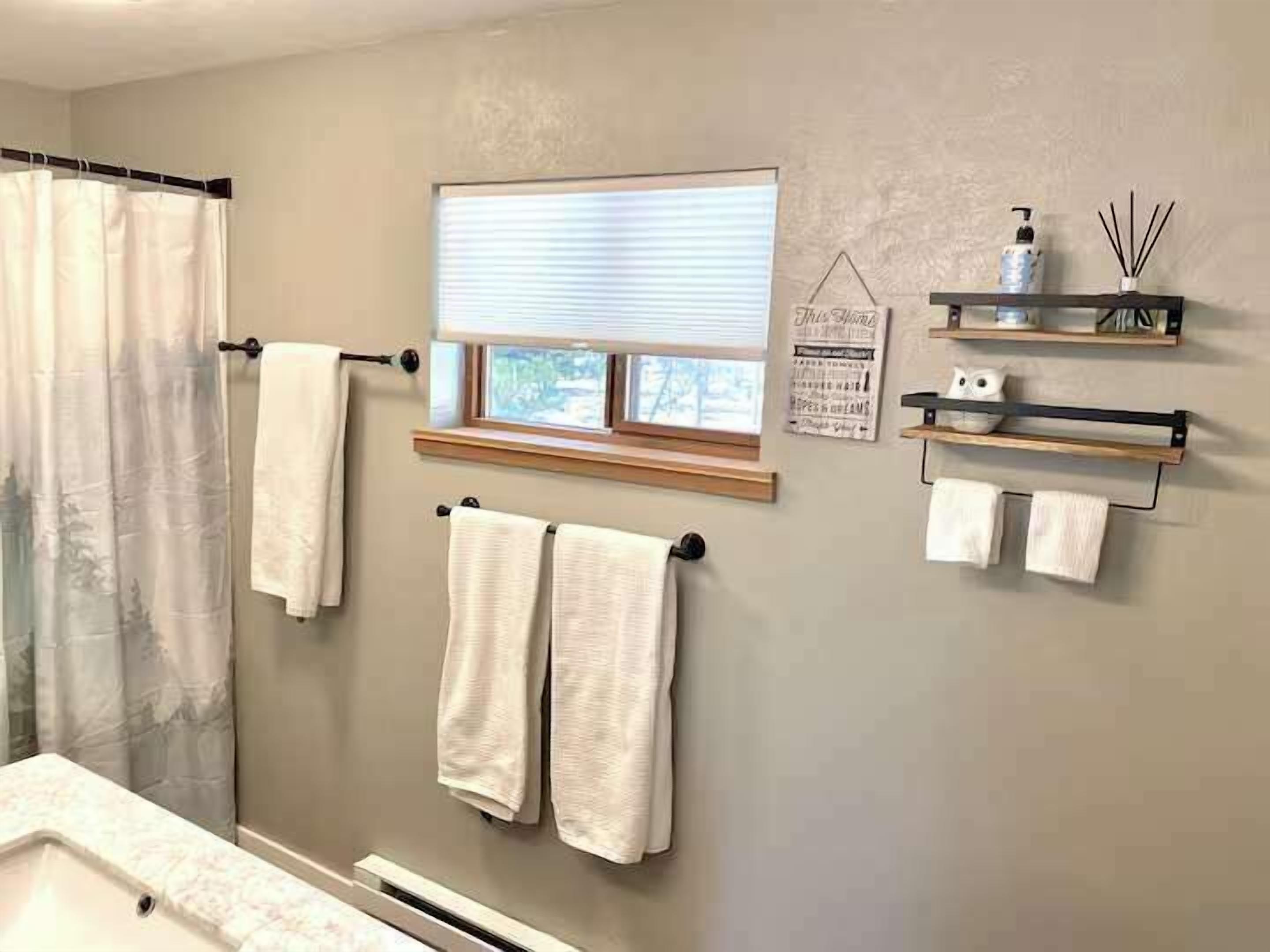 A bathroom with a shower, a window, and towel racks.
