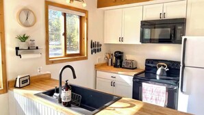 Une cuisine équipée d’un plan de travail en bois, d’un évier, d’une cuisinière, d’un four à micro-ondes et de placards.