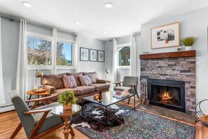 A living room with a fireplace, a sofa, a coffee table, and a rug.
