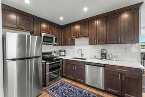 A modern kitchen with dark wood cabinets, stainless steel appliances, and a tiled backsplash.