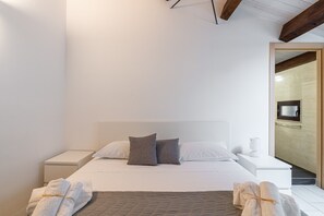 A modern bedroom with a bed, two bedside tables, a TV, and towels.