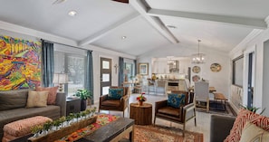 A modern living room with a sofa, armchairs, a coffee table, and a dining area with chairs and a table.