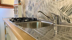 A kitchen with a stainless steel sink, a gas stove, and a modern faucet.