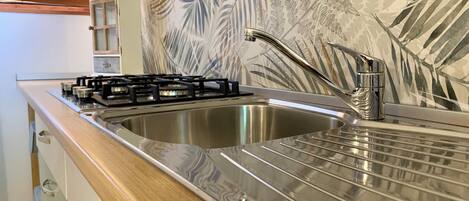 A kitchen with a stainless steel sink, a gas stove, and a modern faucet.
