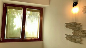 A room with a wooden-framed window, a wall-mounted light fixture, and a stone accent wall.