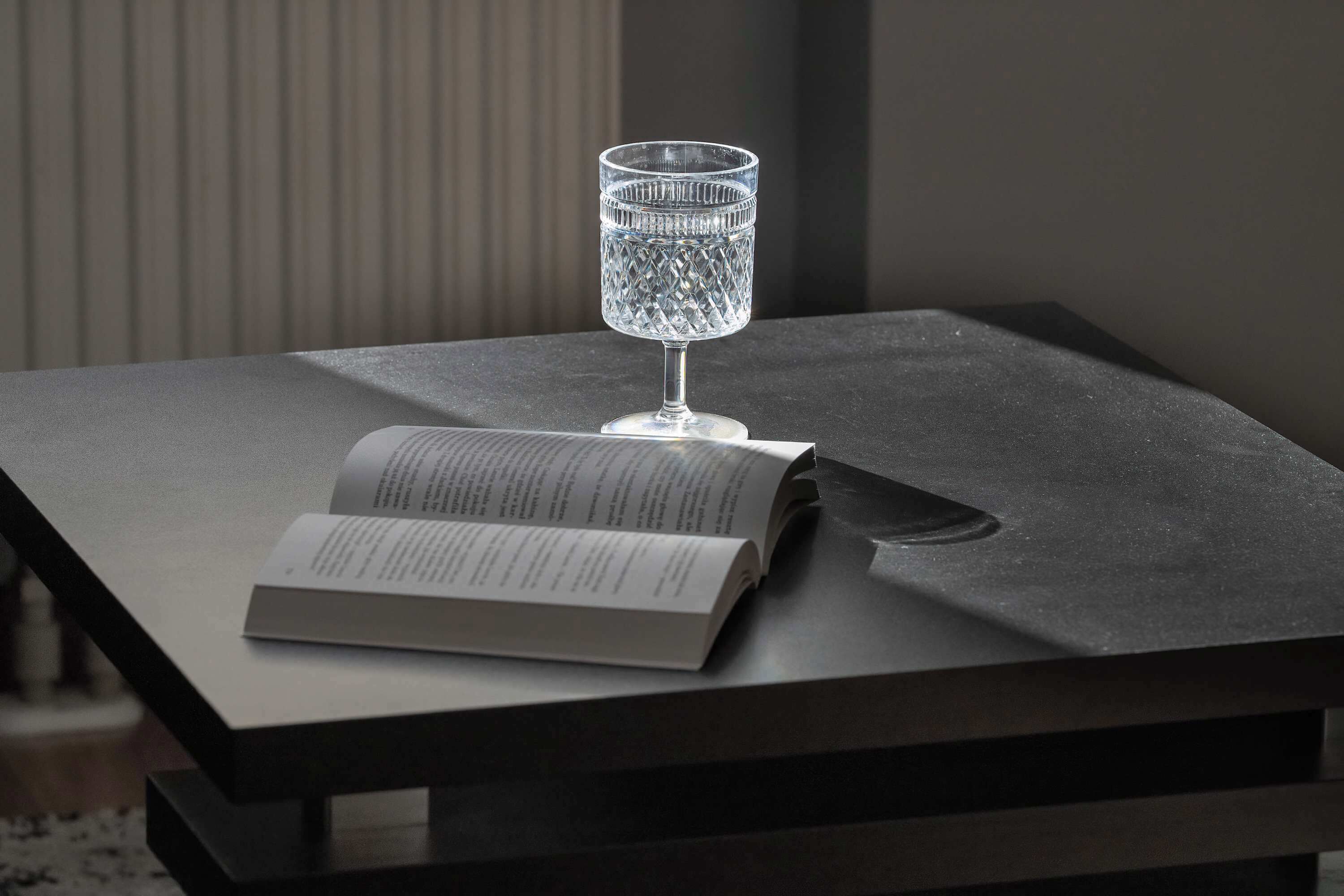 A book and a clear glass on a dark table.