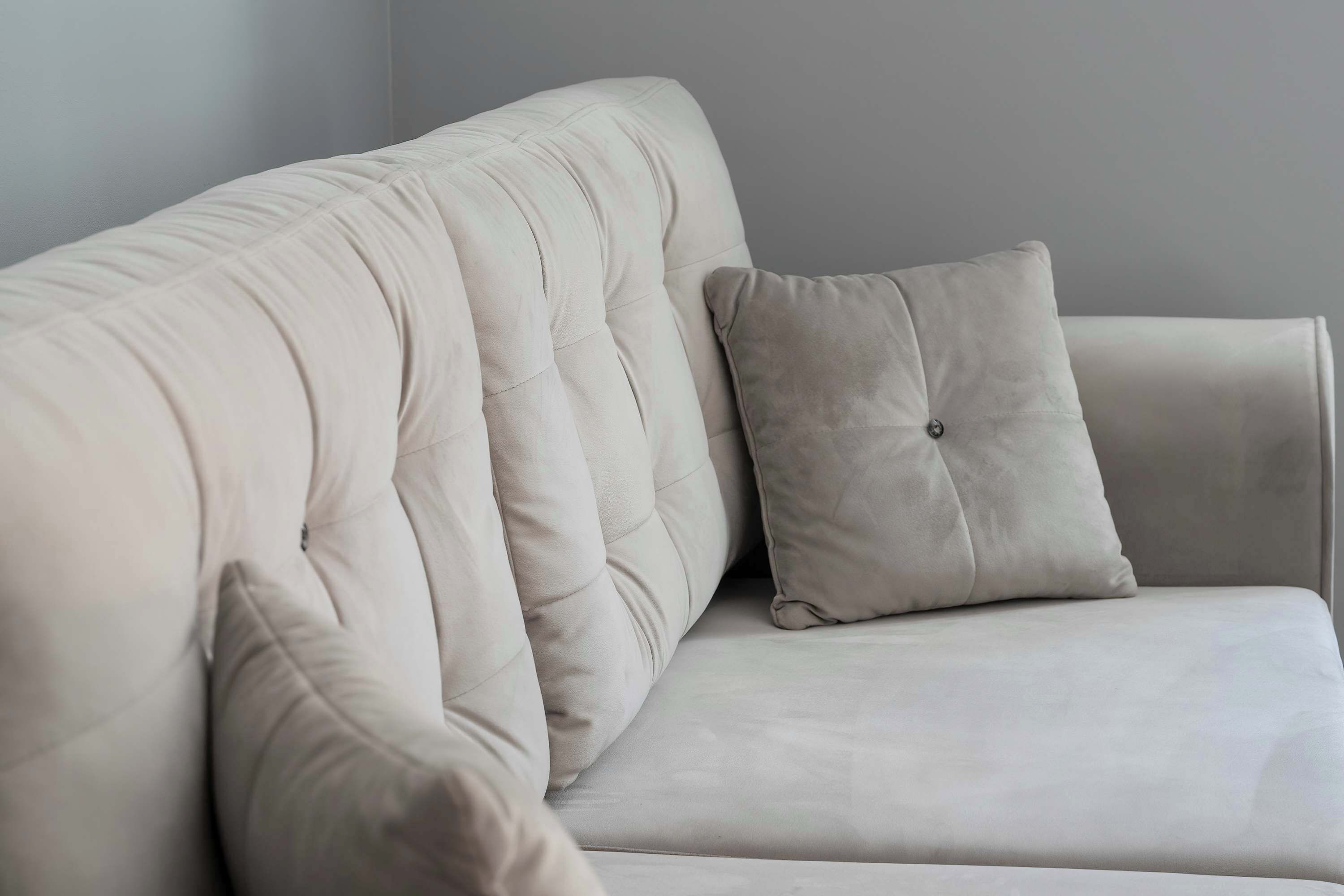 En hvid polstret sofa med en betrukne ryg og en pude.