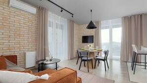 Ein modernes Wohnzimmer mit Ziegelwand, Essbereich und großem Fenster.
