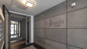 Ein modernes Interieur mit einer gefliesten Wand, auf der 'City Tower 11' abgebildet ist, und einer Glastür zu einem Flur.