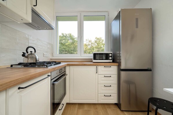 A kitchen with white cabinets, a microwave, a gas stove, and a stainless steel refrigerator.