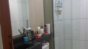 A modern bathroom with a toilet, a sink with toiletries, and a glass shower enclosure. - Complete apartment no turu 5 kms praias aracagy (São José de Ribamar)