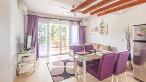 Une cuisine moderne avec un réfrigérateur en acier inoxydable, une table à manger avec des chaises violettes et un ventilateur de plafond.