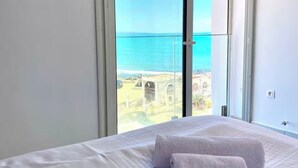 A hotel room with a bed, two towels, and a view of the sea and a historic building. - L'onde Turquoise - Waterfront apartment (Carthage)