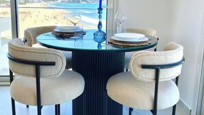 A round table with four chairs, a blue candle, and two wine glasses. - L'onde Turquoise - Waterfront apartment (Carthage)