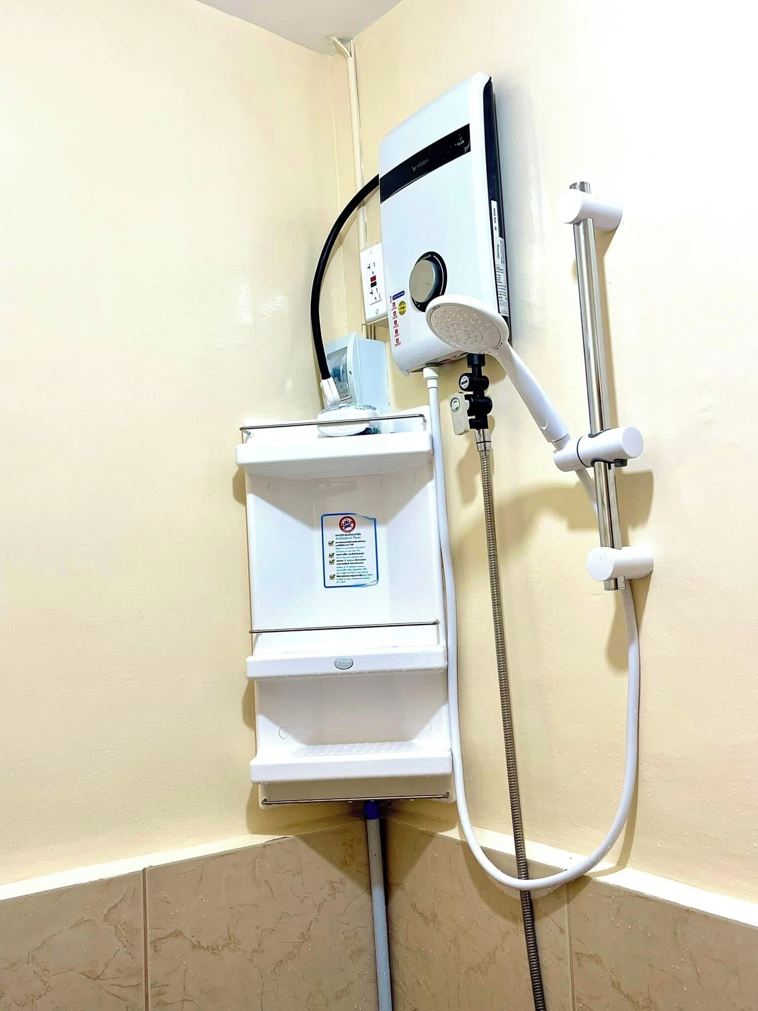 A bathroom with a built-in shower unit, a water heater, and a control panel.