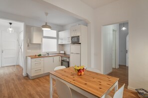 Una cocina moderna con armarios blancos, una mesa de comedor de madera y un frutero.