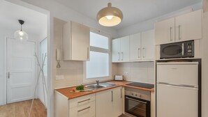 A modern kitchen with white cabinets, a built-in microwave, a double oven, and a wooden countertop.