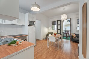 Una cocina moderna con armarios blancos, encimera de madera, un lavamanos y una zona de comedor con mesa y sillas.