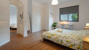 Un dormitorio con cama, escritorio, silla, ventana y puerta.
