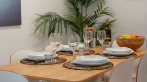 Una mesa de comedor dispuesta con platos, vasos y un bol de fruta.