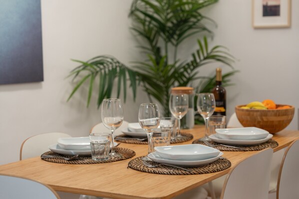 A dining table set with plates, glasses, and a bowl of fruit.