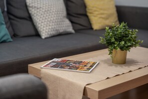 Una revista sobre una mesa, una planta en maceta y un sofá con cojines.