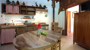 Une cuisine rustique avec des armoires en bois, une table ronde en bois et un poêle.