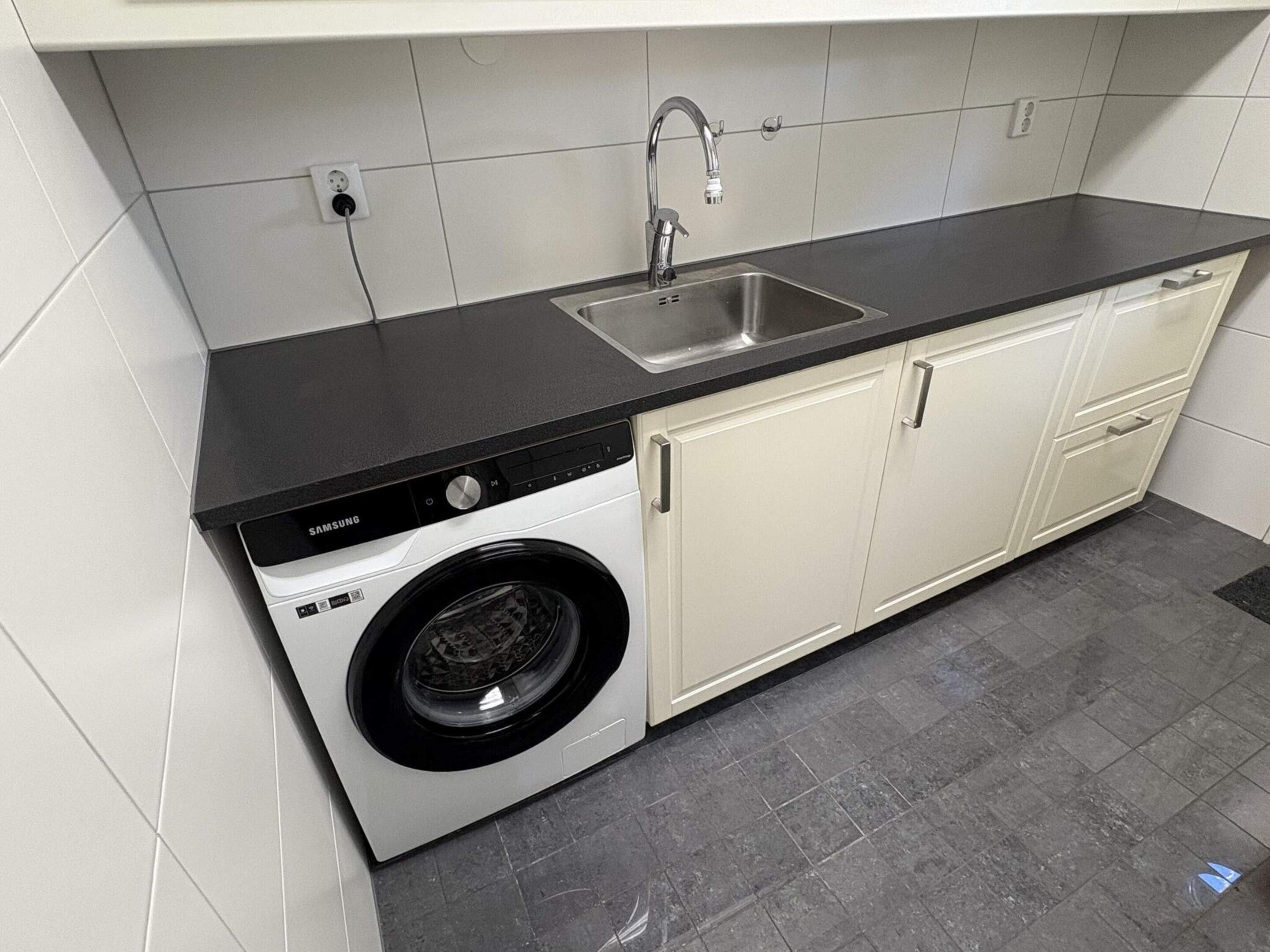 Cocina compacta con lavadora integrada, un lavamanos y una encimera.
