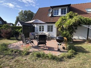 A patio with outdoor furniture, a barbecue grill, and a covered seating area.