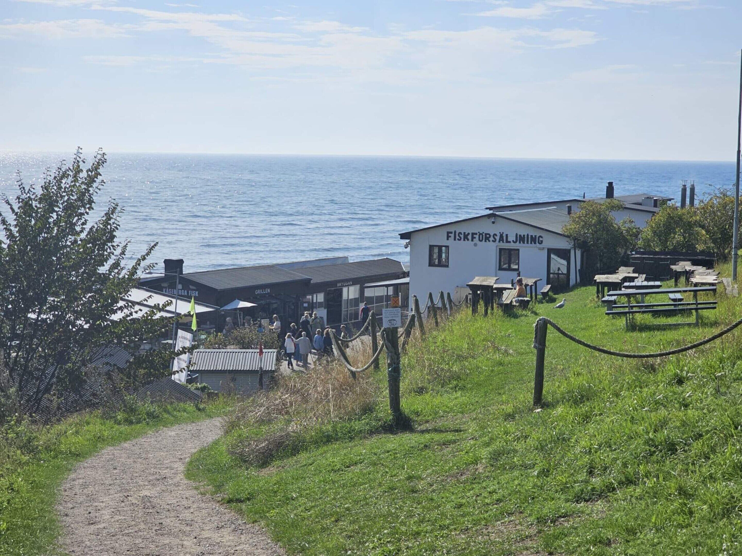 A coastal building named Fiskforsålning with outdoor seating and a view of the sea.