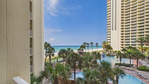 A resort with a pool, palm trees, and a view of the beach and ocean.