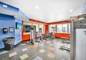 A gym with exercise equipment, a trash bin, and a window with a view. - Emerald Tide Retreat 327-Gulf Views-Sleeps 6 (Panama City Beach)