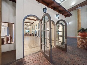 A spacious lobby with arched doorways, a tiled floor, and a large potted plant. - Emerald Tide Retreat 327-Gulf Views-Sleeps 6 (Panama City Beach)