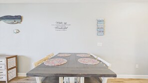 A dining table with four placemats, a wall with inspirational quotes, and a small decorative item.