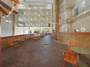 A spacious indoor courtyard with multiple levels of balconies, outdoor seating areas, and a central open space.
