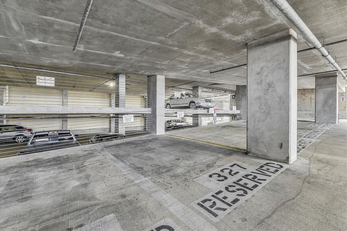 Eine mehrgeschossige Parkgarage mit Betonpfeilern und gekennzeichneten Parkplätzen.