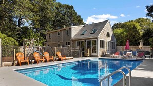 Ein Schwimmbecken mit Liegestühlen und einem Haus im Hintergrund.
