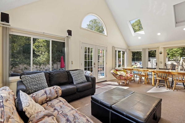 A spacious living area with a large couch, ottoman, and dining table.