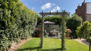 Ein Garten mit einer Pergola, einem Tisch und Stühlen unter einem Baldachin.