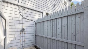 A wooden deck adjacent to a white fence with a metal gate. - Cape Cod Family Escape w/ Pool, Game Room & Patio (Falmouth)