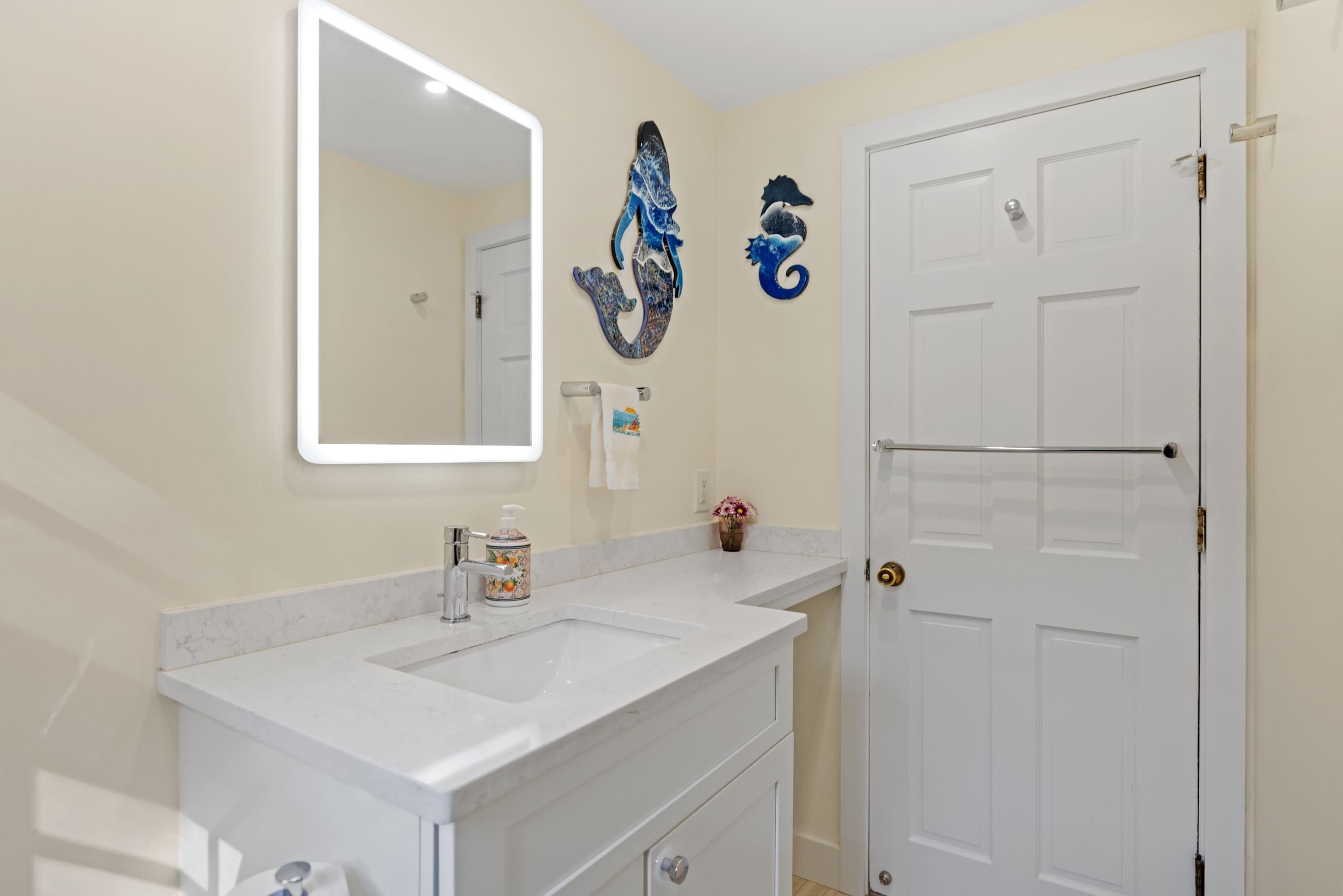A bathroom with a double sink, a mirror, and a door.